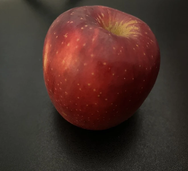A man holding an apple against a plain background, illustrating the AI enhancement process in action. (AI)